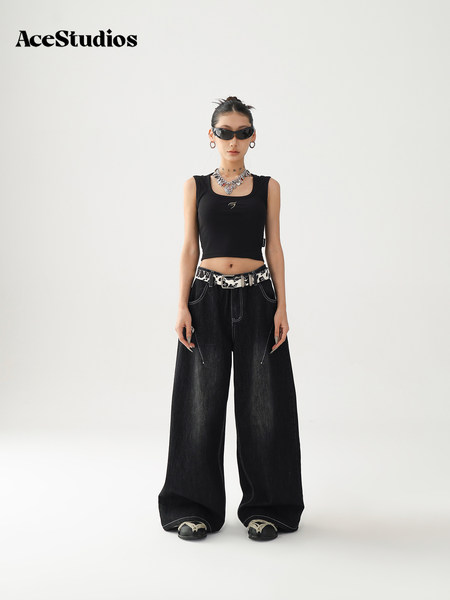 Model wearing a black sleeveless crop top with oversized black wide-leg jeans