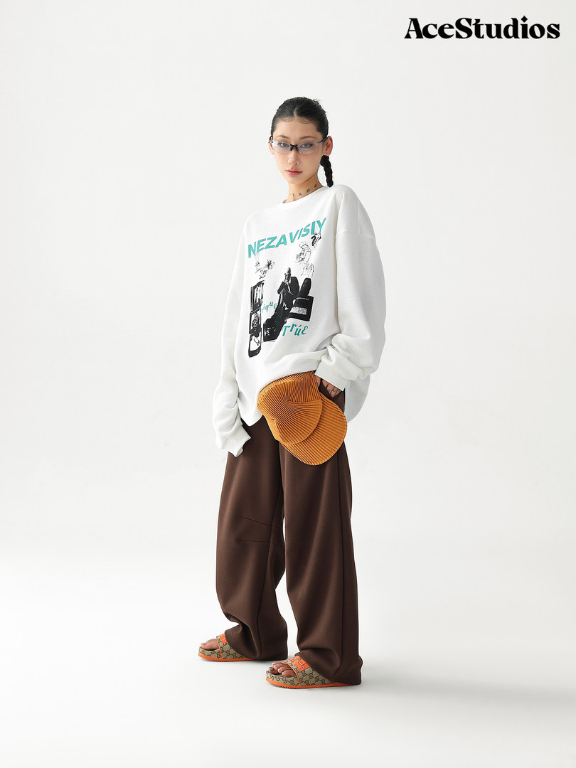Model wearing a graphic oversized sweatshirt with wide brown pants and slide sandals