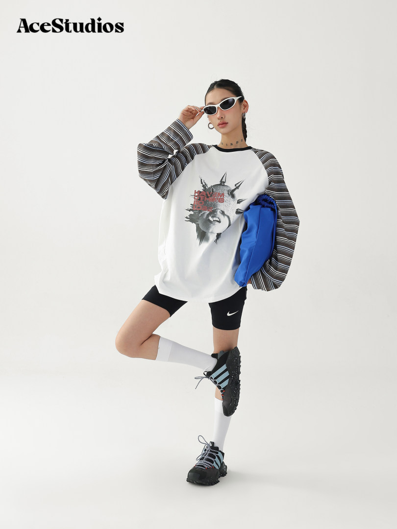 Fashion model wearing a graphic long-sleeve top, biker shorts, and sneakers