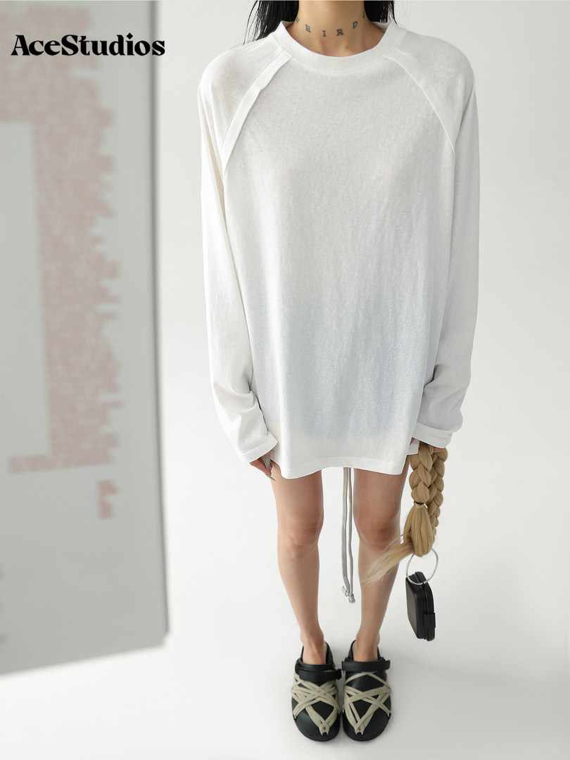 Model wearing an oversized white long-sleeve top with black sandals