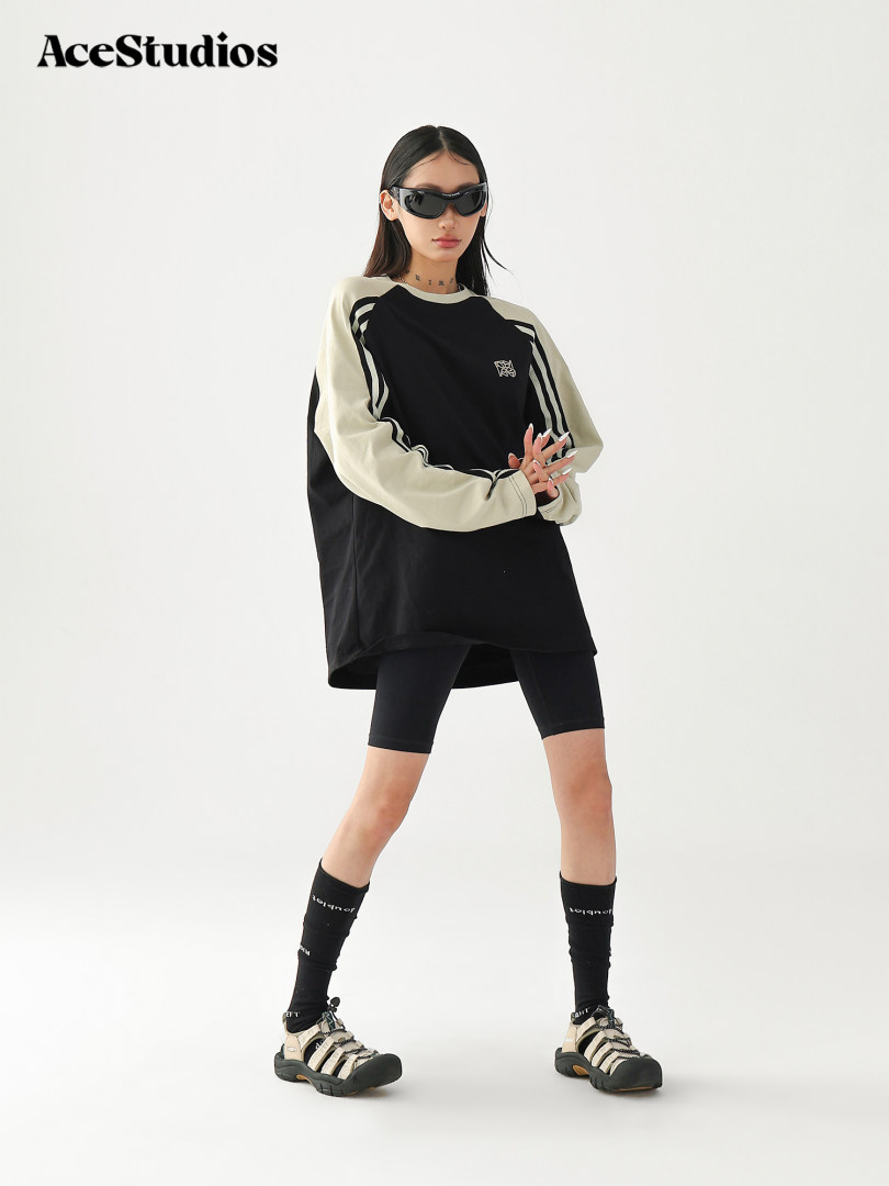 Model wearing a black and cream oversized long-sleeve top with biker shorts and sneakers