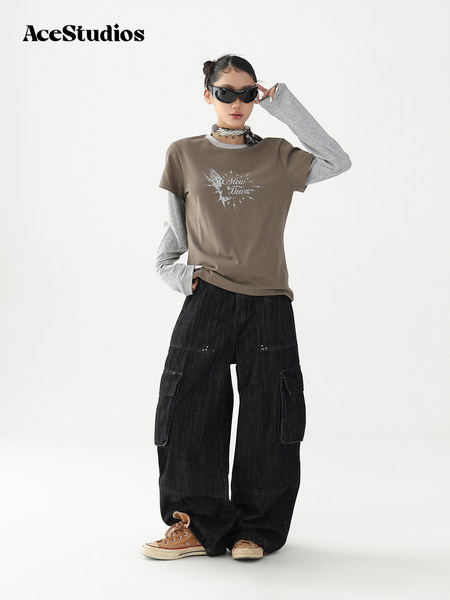Model wearing a layered streetwear outfit with a graphic tee, long sleeves, cargo pants, and sneakers