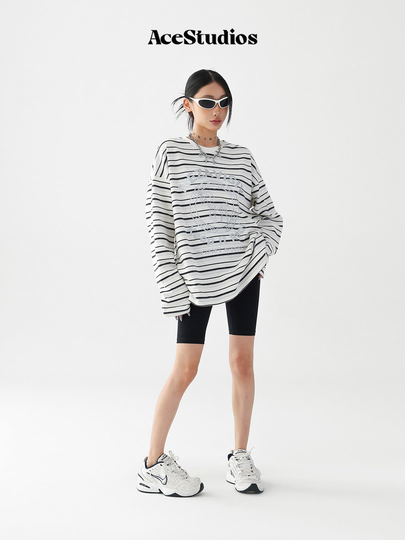 Model wearing an oversized striped long-sleeve shirt with black biker shorts and sneakers