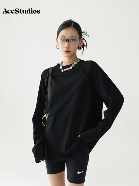 Model wearing a black oversized long-sleeve top with black fitted shorts and accessories