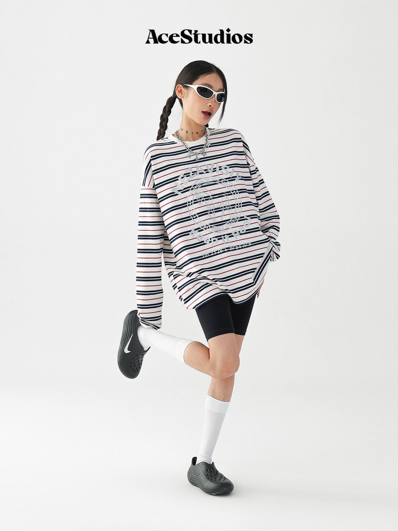 Model wearing a striped oversized graphic long-sleeve top with shorts and sneakers