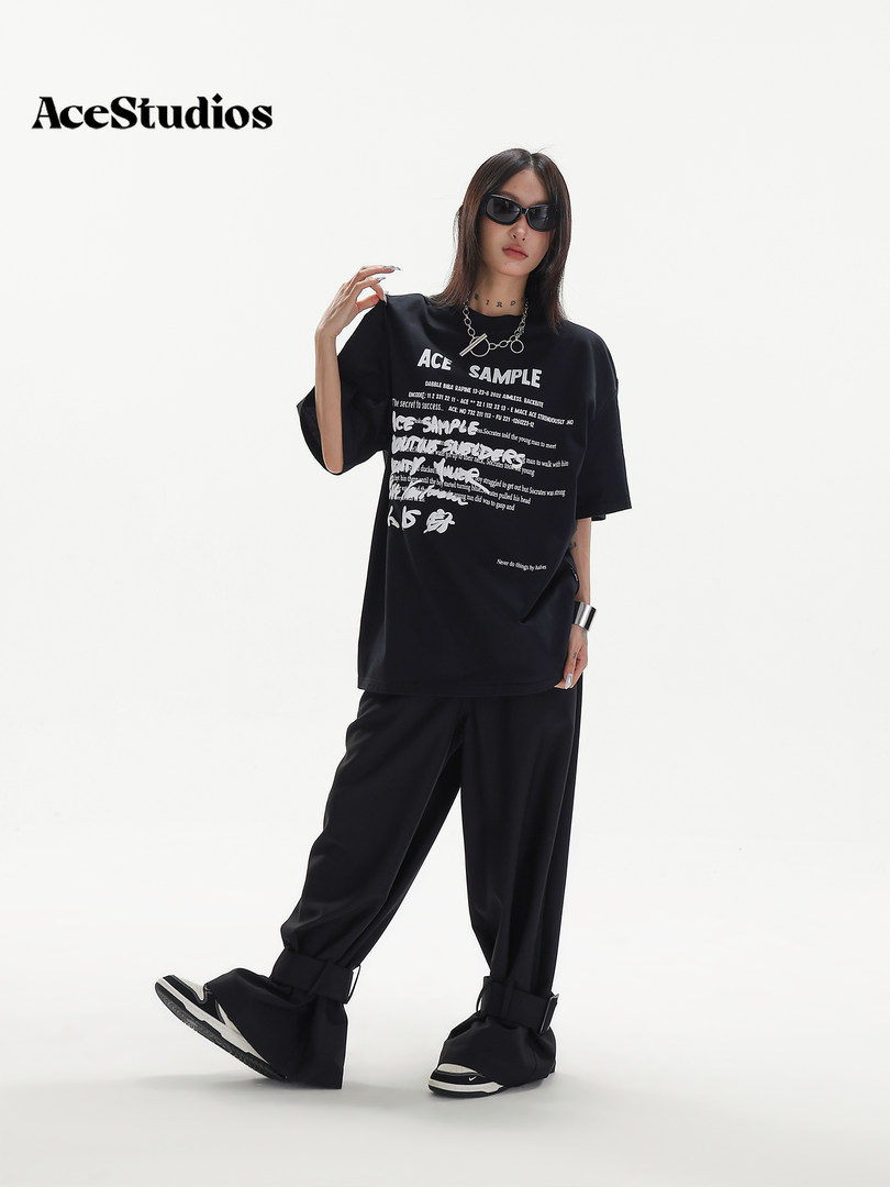 Model wearing an oversized black graphic T-shirt with wide-leg black pants and sneakers