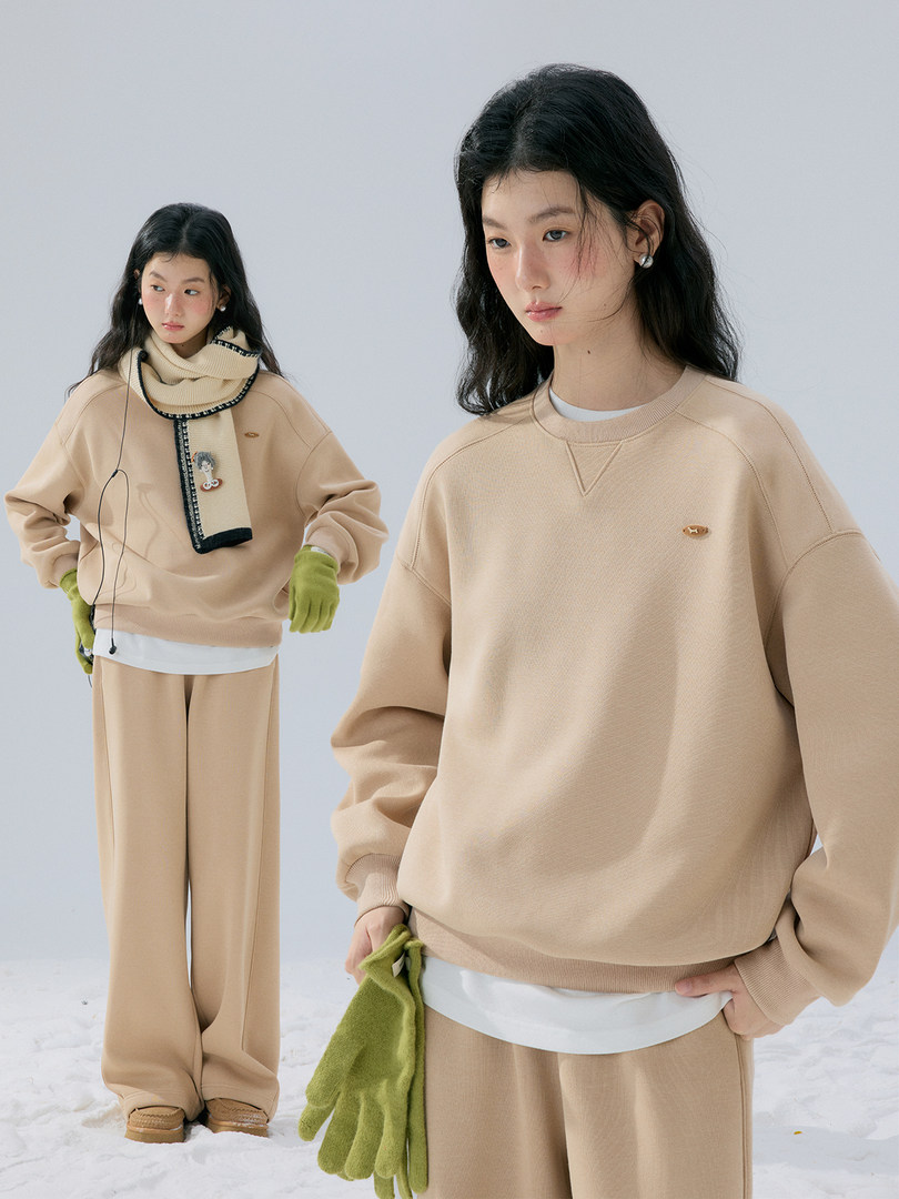 Beige oversized sweatshirt and wide-leg pants worn by a model in a winter outfit