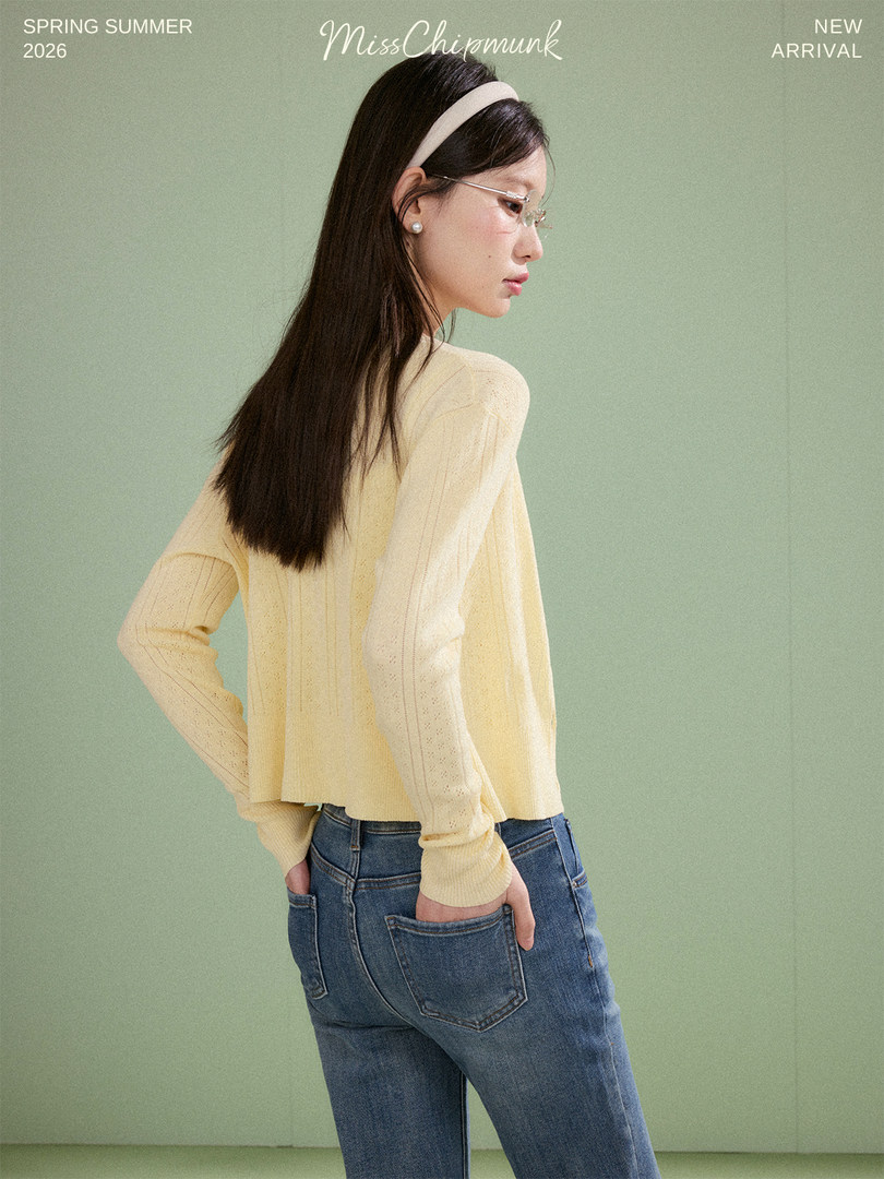 Model wearing a light yellow knit top with blue jeans on a plain background