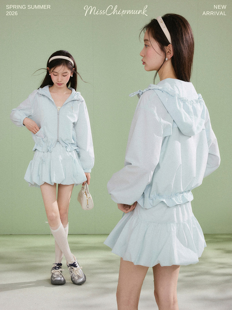 Light blue sheer hooded jacket and ruffled mini skirt outfit worn by a model