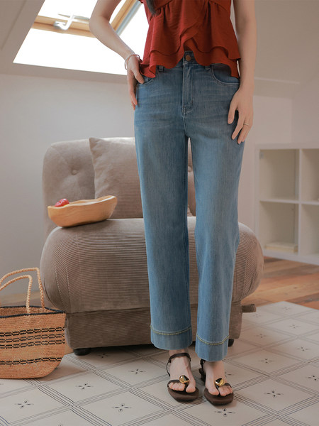 Model wearing light blue straight-leg jeans with a red top and sandals indoors