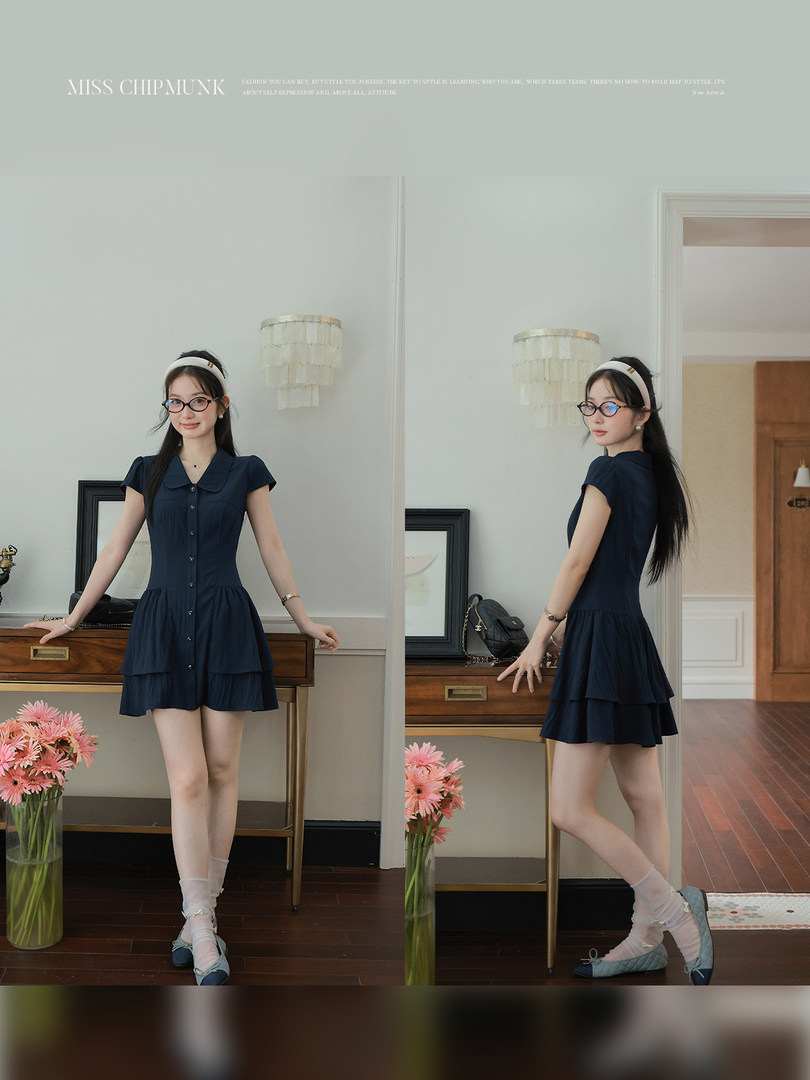Navy short-sleeve tiered dress worn by a model indoors