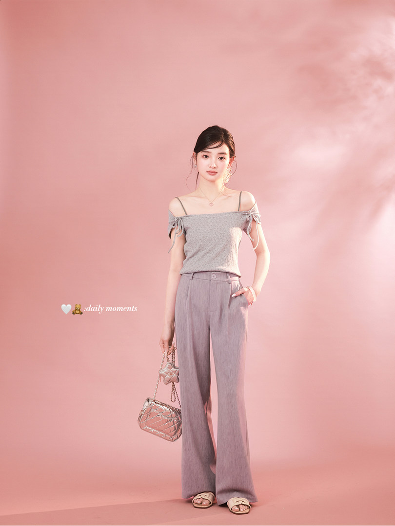Woman modeling a gray off-shoulder top with wide-leg pants and a handbag