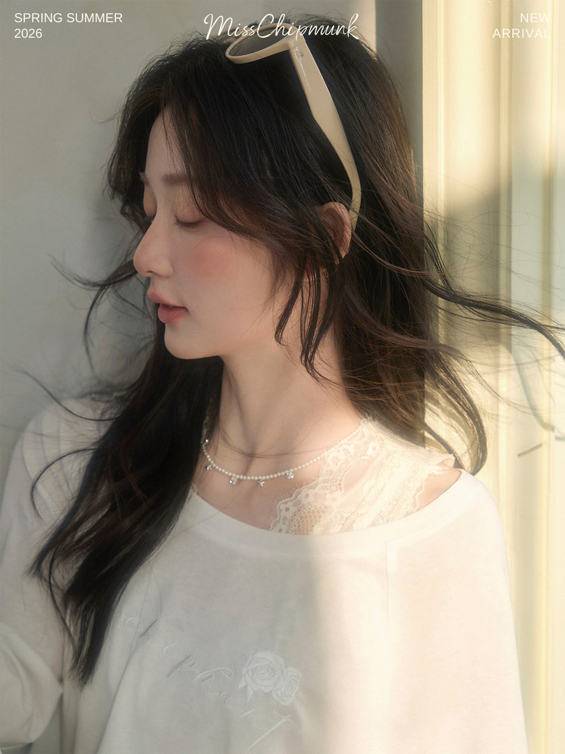 Woman wearing a white lace-trim top and pearl necklace