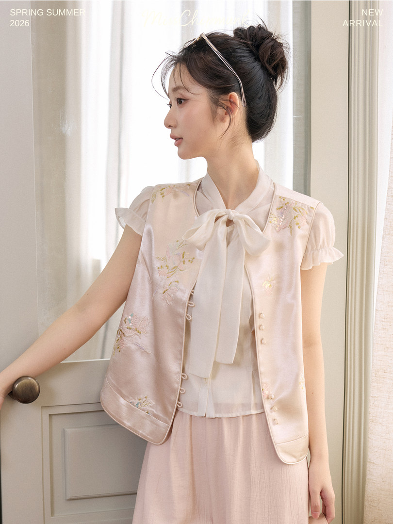 Model wearing a light pink feminine blouse and embroidered vest set