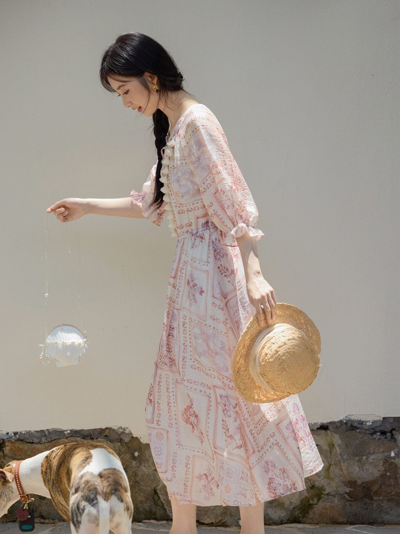 Pink patterned midi dress worn by a woman outdoors
