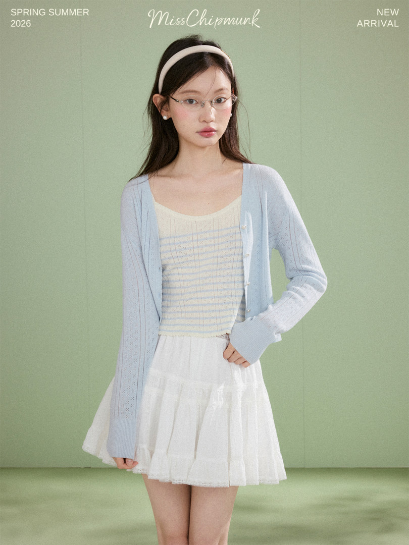 Model wearing a light blue cardigan over a striped top with a white skirt