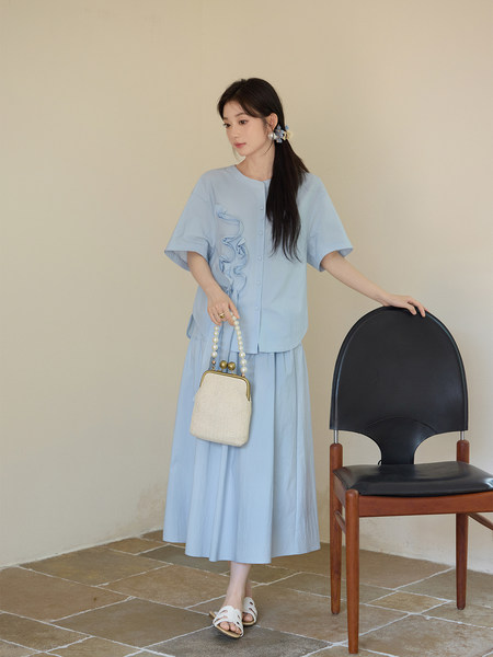 Light blue two-piece outfit worn by a model with a matching skirt and short-sleeve top