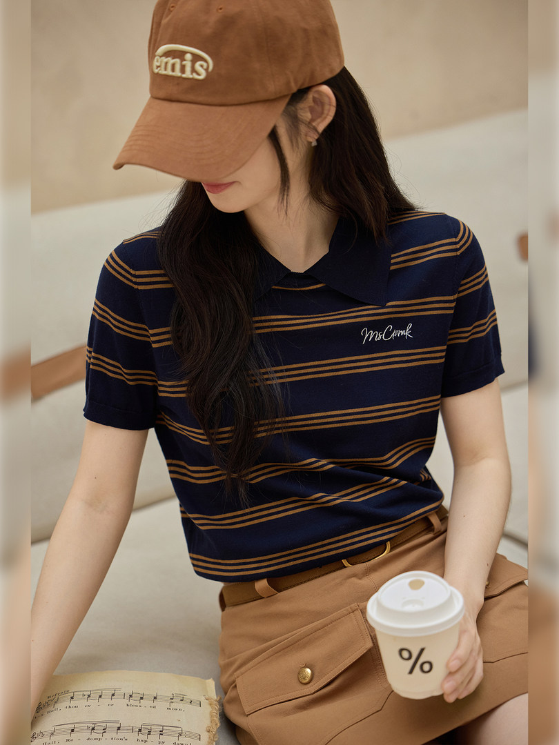 Model wearing a navy striped polo shirt with tan shorts and a brown cap