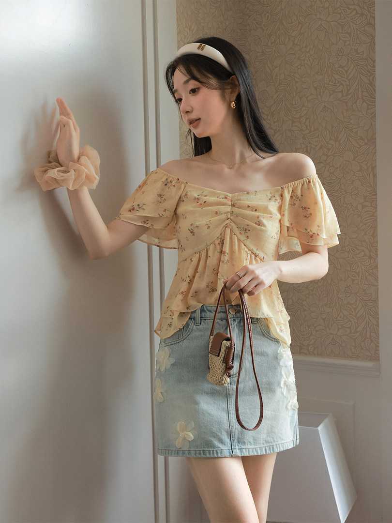 Woman wearing an off-shoulder floral top with a light denim mini skirt