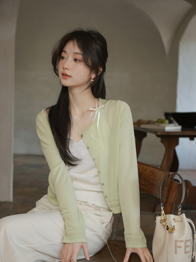 Woman wearing a light green cardigan with a white top and cream pants
