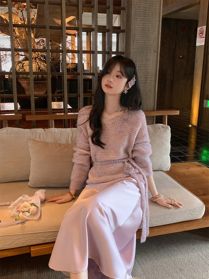 Woman wearing a pastel pink knit wrap top with a matching satin skirt
