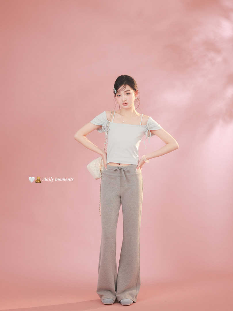 Model wearing a light gray off-shoulder top and wide-leg pants on a pink background
