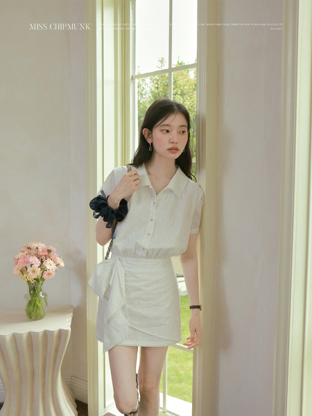 White blouse and mini skirt outfit worn by a model indoors