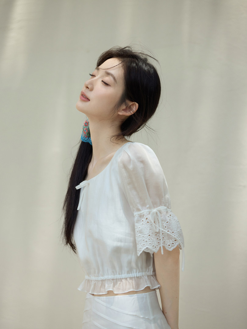 Woman wearing a white cropped blouse with lace sleeves