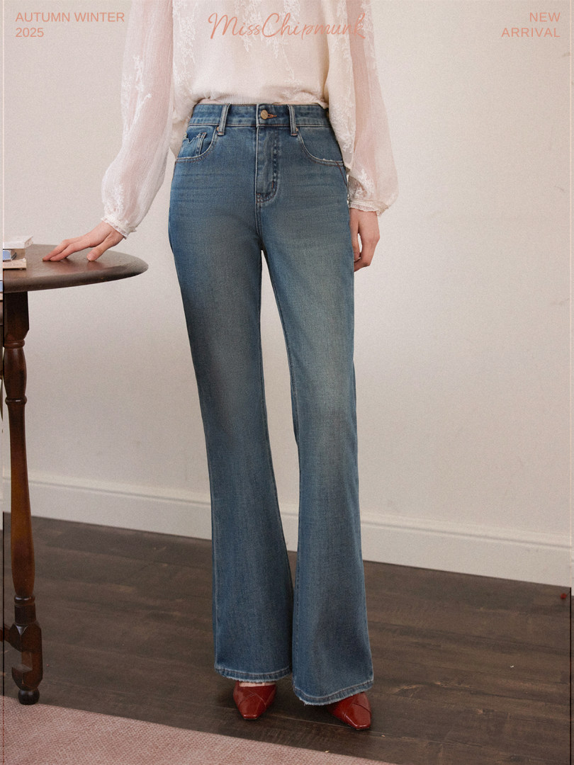 Model wearing high-waisted blue flared jeans with a light blouse and red shoes