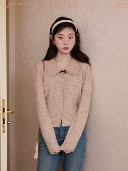 Young woman wearing a beige fuzzy cardigan with a Peter Pan collar and jeans