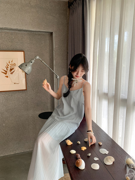 Woman wearing a light gray spaghetti-strap dress in a bright indoor setting
