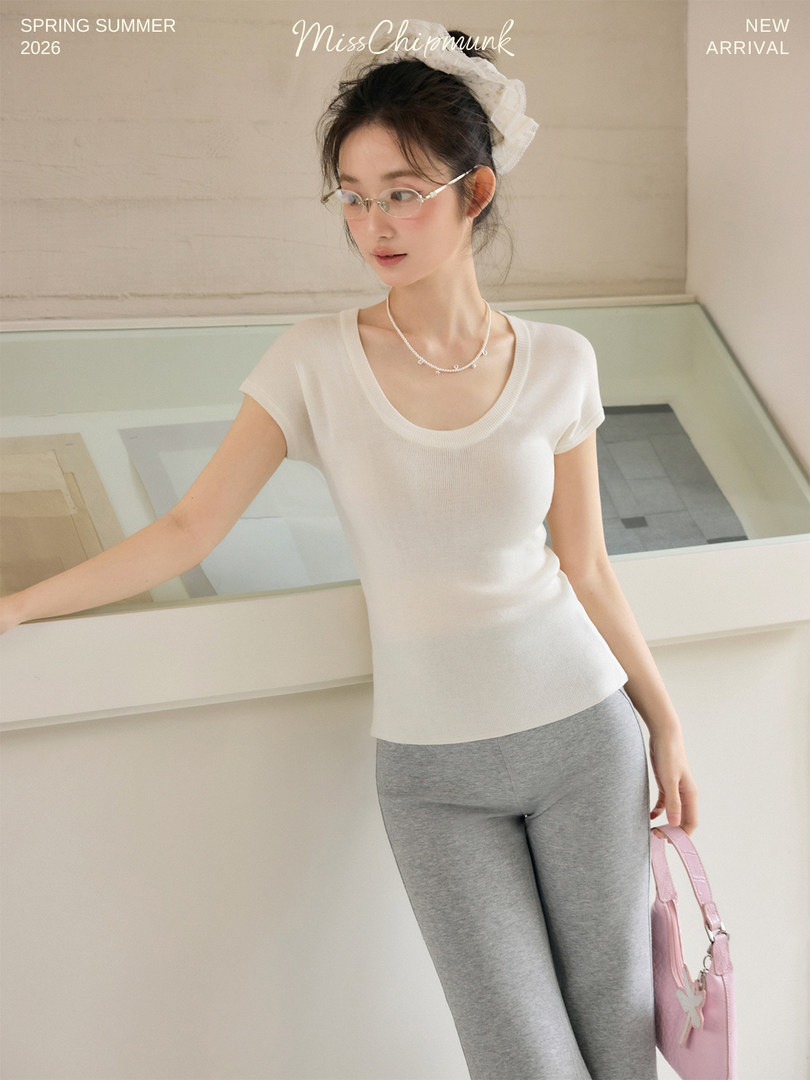 Woman modeling a white short-sleeve top with gray leggings, shown as a new arrival fashion photo
