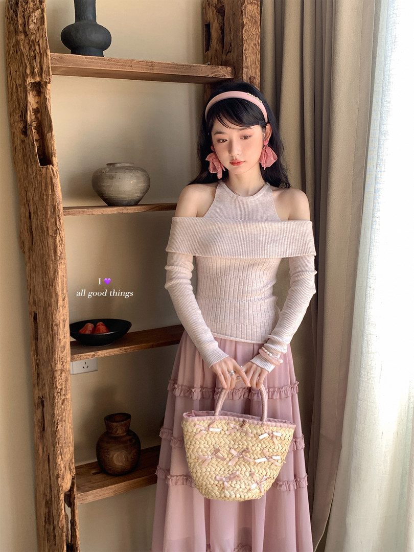 Woman wearing a pink off-shoulder knit top with a matching pink skirt and woven handbag