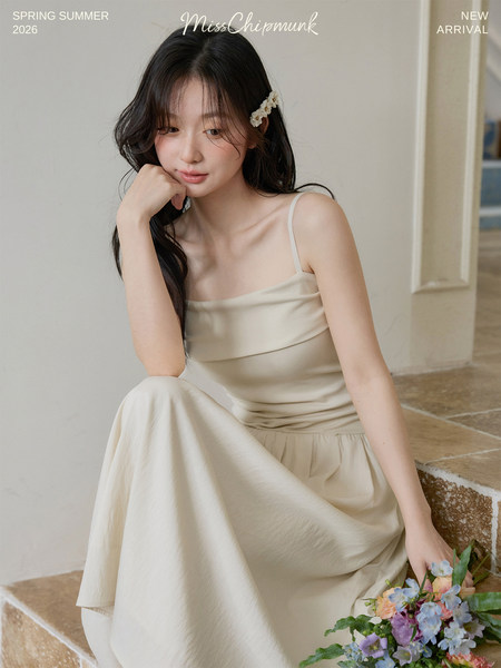 Model wearing a cream sleeveless dress with a flowing skirt