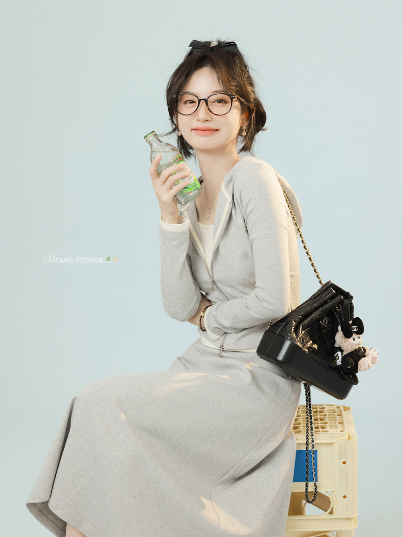 Woman wearing a light gray matching skirt set with a black shoulder bag