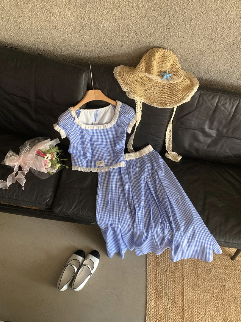 Blue gingham two-piece outfit with a straw hat and flats displayed on a couch