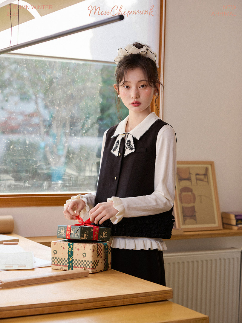 Model wearing a black and white layered blouse and vest outfit
