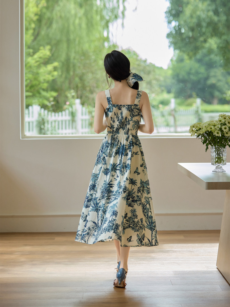 Sleeveless tropical floral midi dress worn by a model indoors