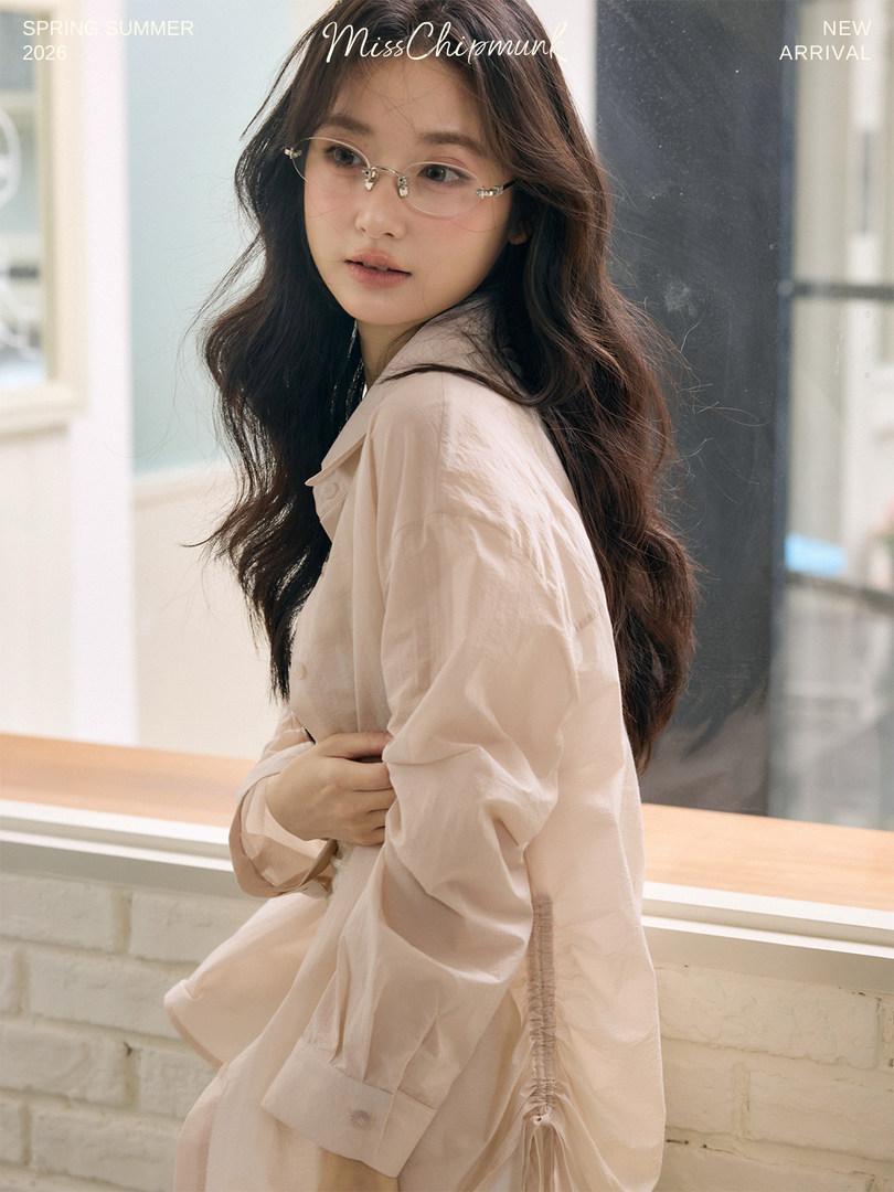 Model wearing a light pink long-sleeve blouse with glasses