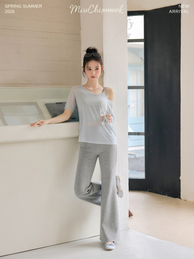 Model wearing a light gray off-shoulder top and wide-leg pants in a studio setting