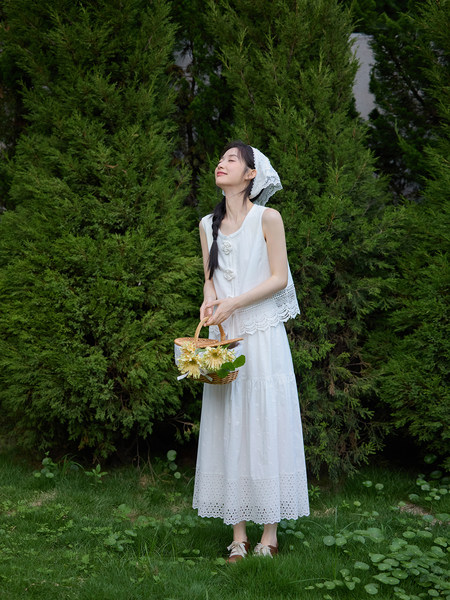 Woman wearing a white sleeveless lace dress outdoors with a basket of flowers