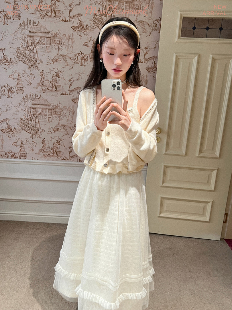 Woman wearing a cream cardigan and white dress in a mirror selfie