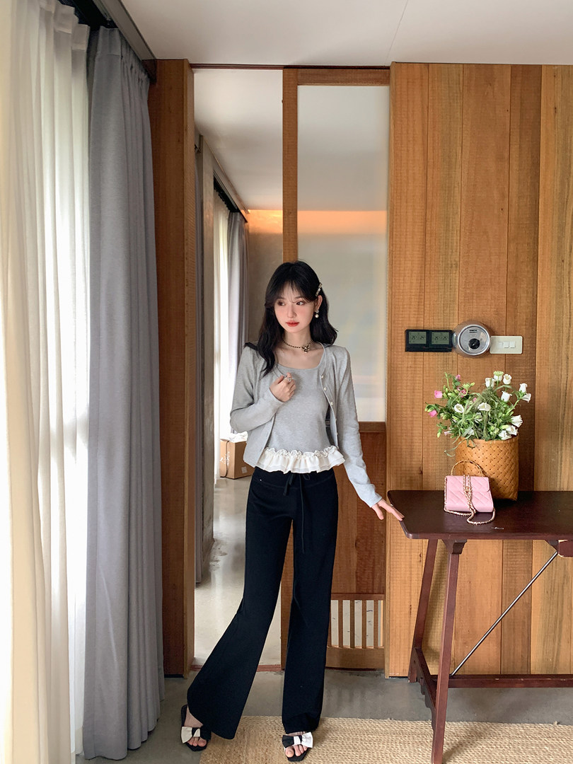 Woman wearing a gray cardigan and top with black wide-leg pants in a room setting