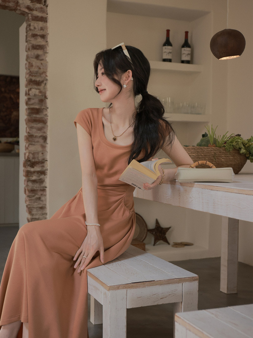 Woman wearing a peach maxi dress seated indoors