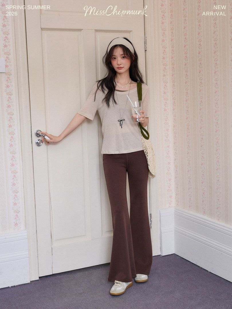 Model wearing a beige top with brown flared pants and casual accessories