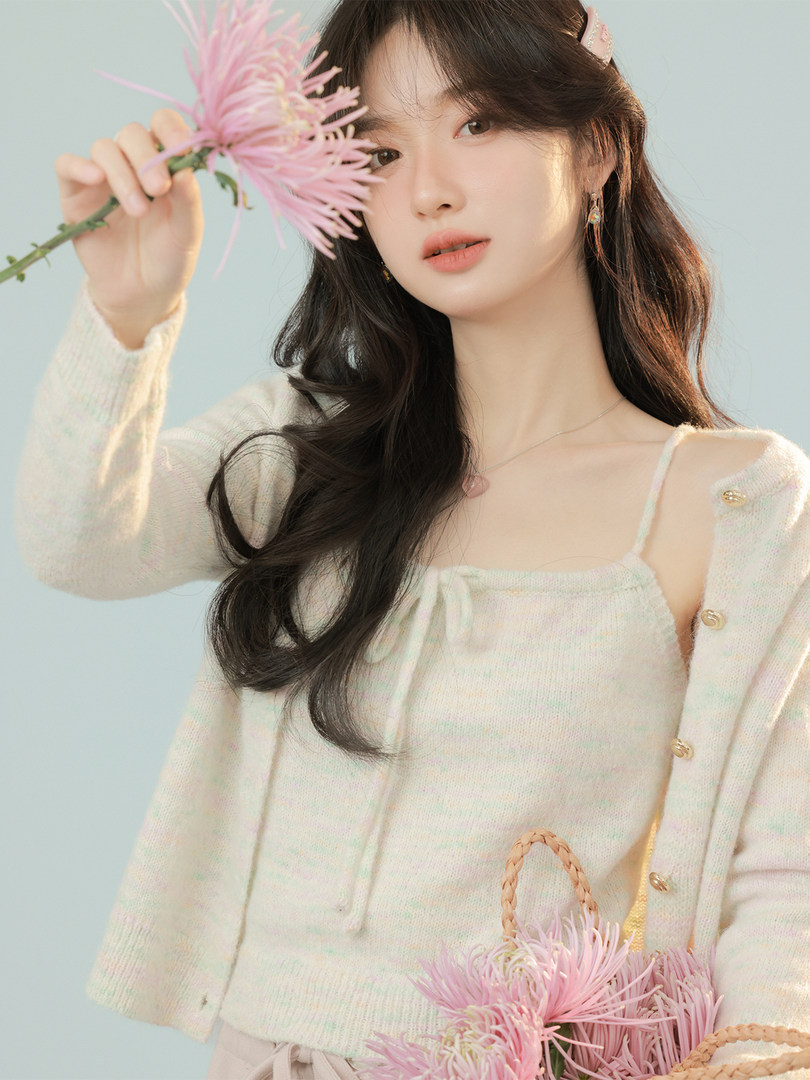 Woman wearing a cream knit cardigan and camisole top