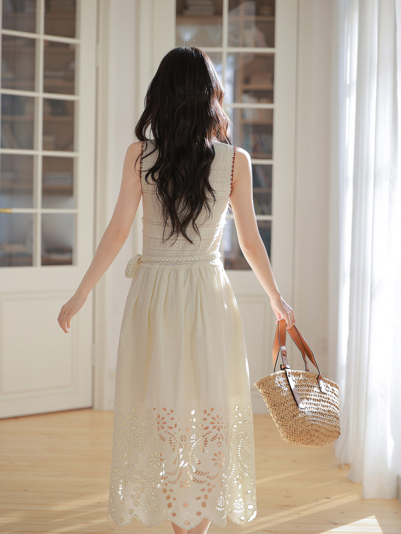 Cream sleeveless embroidered maxi dress worn by a model holding a woven tote bag