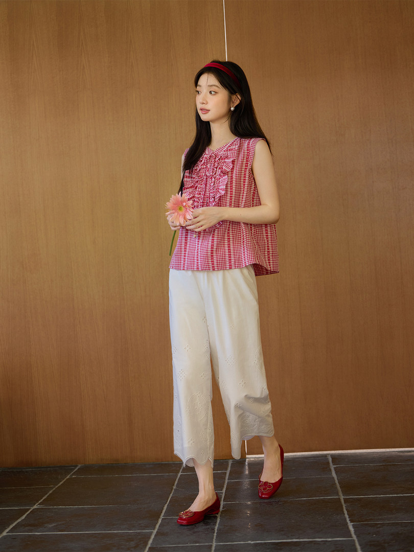 Model wearing a red gingham sleeveless top with white cropped pants and red flats