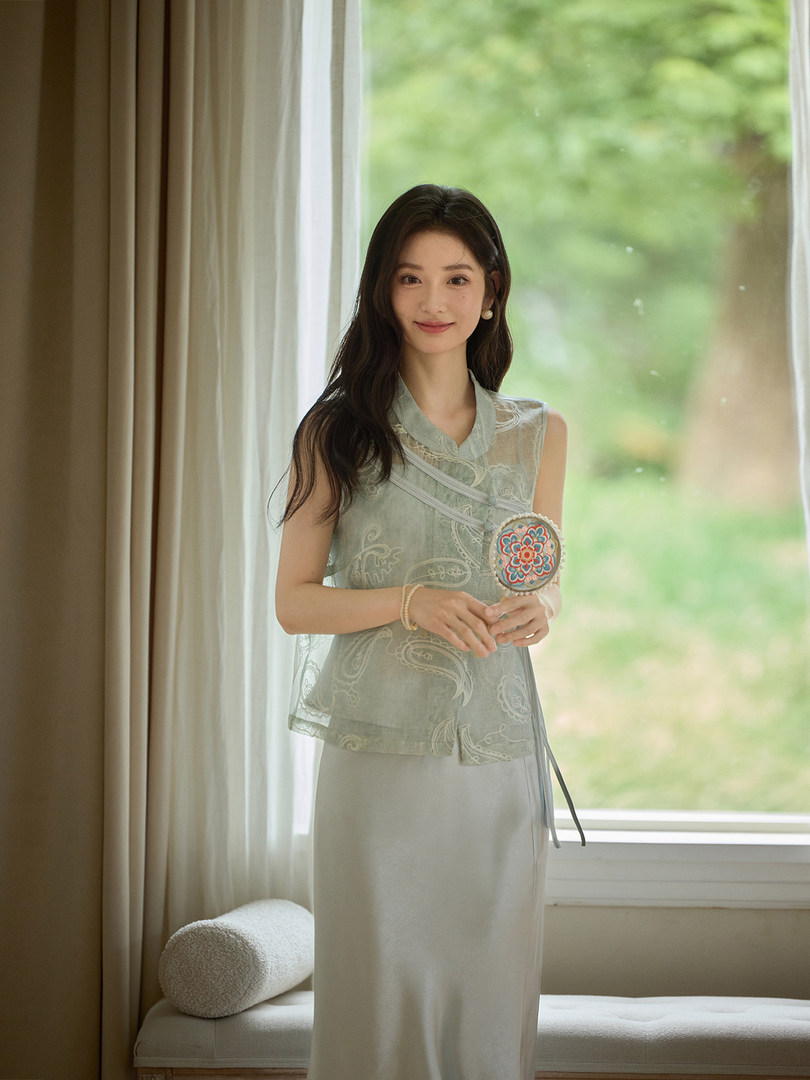 Model wearing a light green sleeveless embroidered top with a matching long skirt