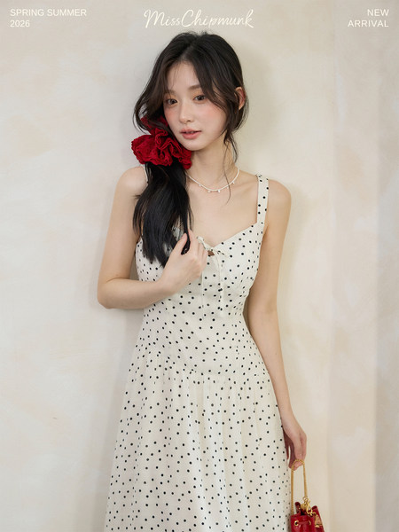 Model wearing a white polka dot sleeveless dress with a fitted bodice
